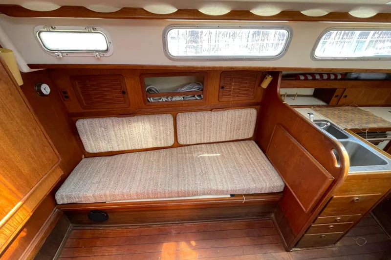 Slide: The Image of 1982 Sabre 34 sailboat interior with wooden cabinetry, cushioned seating, and compact kitchen area. - 25