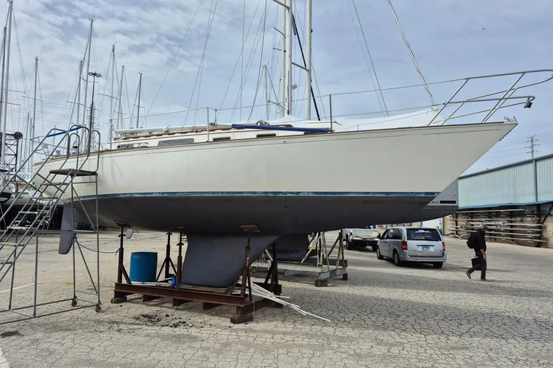 Slide: The Image of 1982 Sabre 34 sailboat on dry dock with ladder and vehicles nearby. - 3