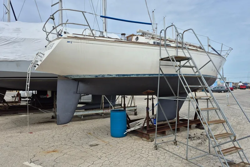 Slide: The Image of 1982 Sabre 34 sailboat on dry dock with ladder and blue barrel nearby. - 6