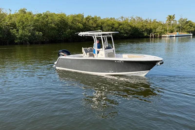 Slide: The Image of 2023 Sportsman Open 232 Center Console boat cruising on calm water near lush greenery. - 10
