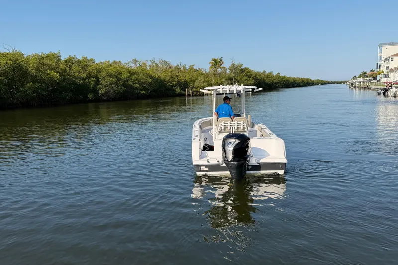Slide: The Image of 2023 Sportsman Open 232 Center Console boat navigating a calm waterway. - 14