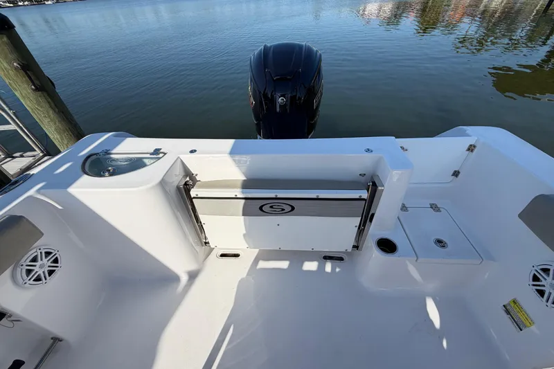 Slide: The Image of 2023 Sportsman Open 232 Center Console boat interior with motor, docked on calm water. - 26