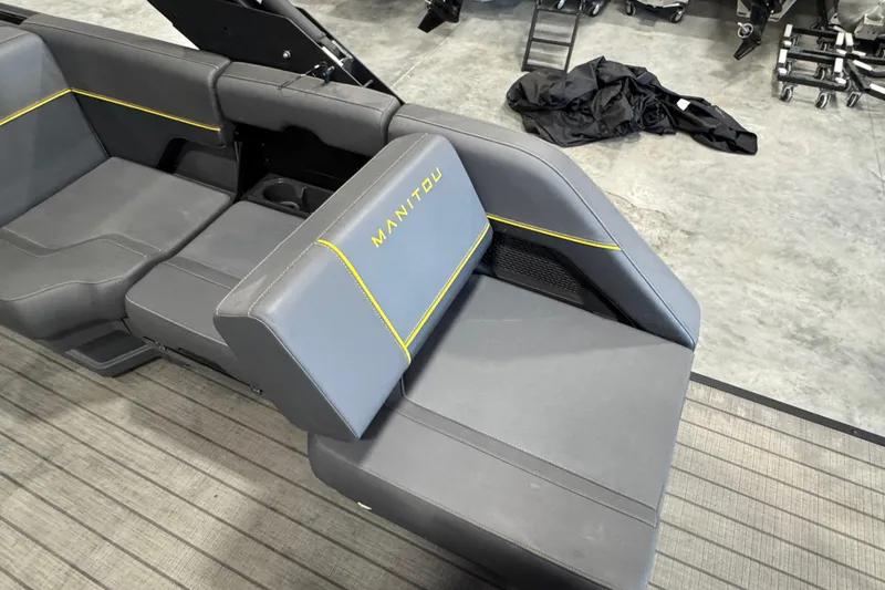Slide: The Image of 2025 Manitou 24 Explore boat interior with gray seating and yellow accents. - 13