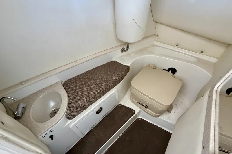 Slide: The Image of Interior of a 2005 Cobalt 282 boat featuring a compact bathroom with sink and portable toilet. - 12