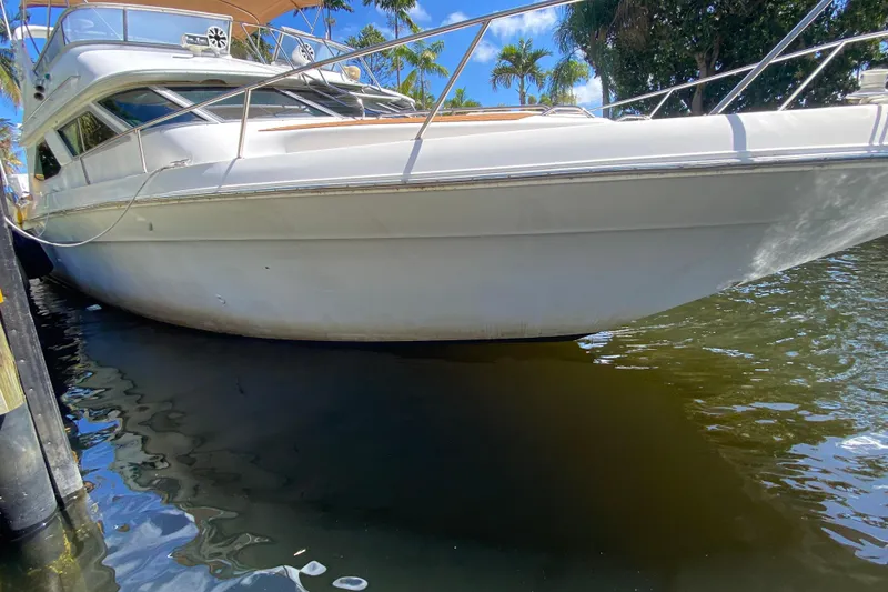 Slide: The Image of 1994 Sea Ray 440 Express Bridge yacht docked, reflecting on calm water under a clear sky. - 11