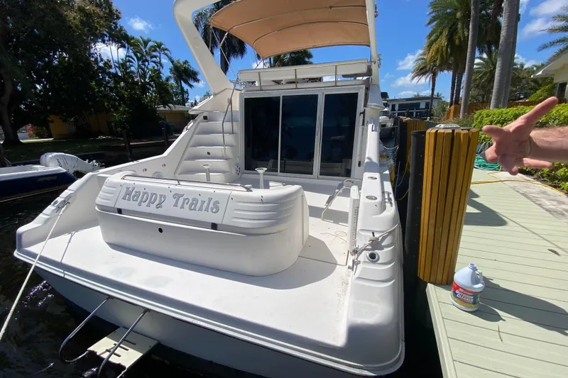 Slide: The Image of 1994 Sea Ray 440 Express Bridge yacht docked, featuring "Happy Trails" on the stern. - 13