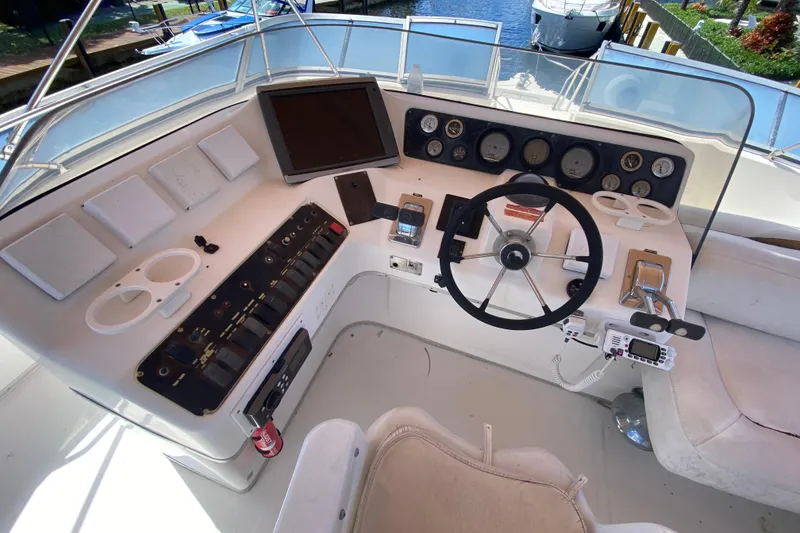 Slide: The Image of 1994 Sea Ray 440 Express Bridge helm with steering wheel, gauges, and control panel. - 15