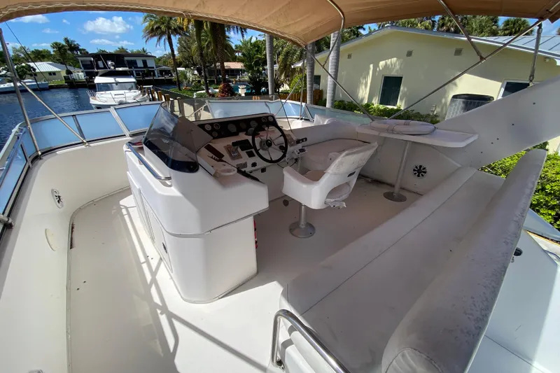 Slide: The Image of 1994 Sea Ray 440 Express Bridge yacht helm with seating, docked by waterfront homes. - 16
