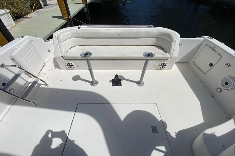Slide: The Image of 1994 Sea Ray 440 Express Bridge boat deck with seating and ladder, docked by water. - 20