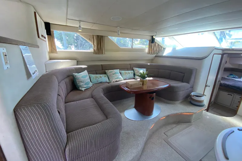 Slide: The Image of Interior of 1994 Sea Ray 440 Express Bridge with plush seating and wooden table. - 23