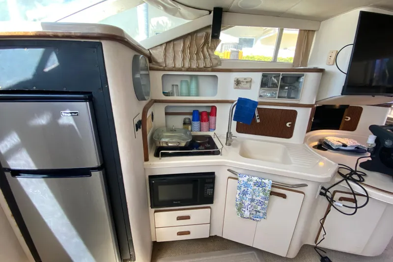 Slide: The Image of 1994 Sea Ray 440 Express Bridge kitchen with appliances, sink, and storage. - 29