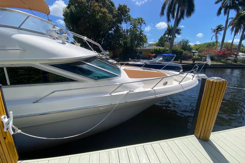 Slide: The Image of 1994 Sea Ray 440 Express Bridge yacht docked by palm trees under a clear blue sky. - 3