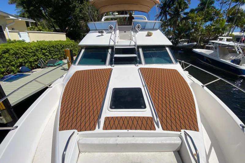 Slide: The Image of 1994 Sea Ray 440 Express Bridge yacht docked, featuring spacious deck and sleek design. - 4