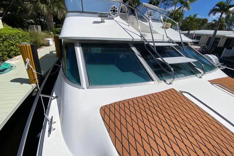Slide: The Image of 1994 Sea Ray 440 Express Bridge yacht docked, featuring sleek design and spacious deck. - 6