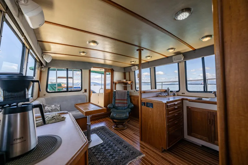 Slide: The Image of Interior of a 1997 Nordic Tug 42, featuring a cozy seating area and kitchenette. - 11