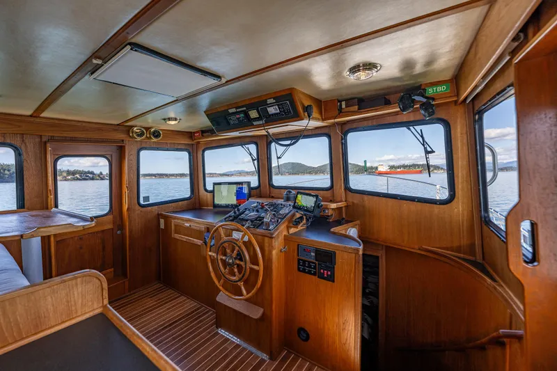 Slide: The Image of Interior of a 1997 Nordic Tug 42 boat, featuring a wooden helm and navigation equipment. - 12