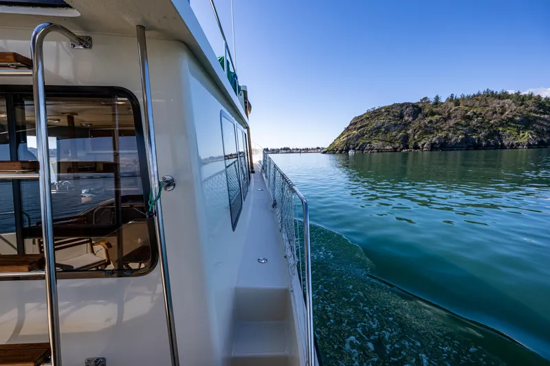 Slide: The Image of 1997 Nordic Tug 42 cruising near a rocky island under clear blue skies. - 29
