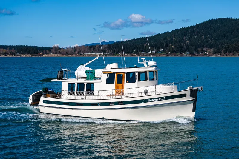 Slide: The Image of 1997 Nordic Tug 42 cruising on a scenic blue lake with forested hills. - 38