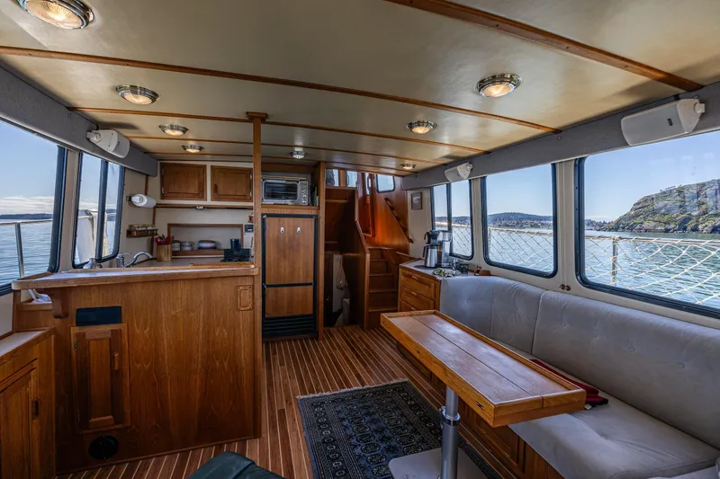 Slide: The Image of Interior of a 1997 Nordic Tug 42, featuring a cozy wooden cabin with scenic ocean views. - 4