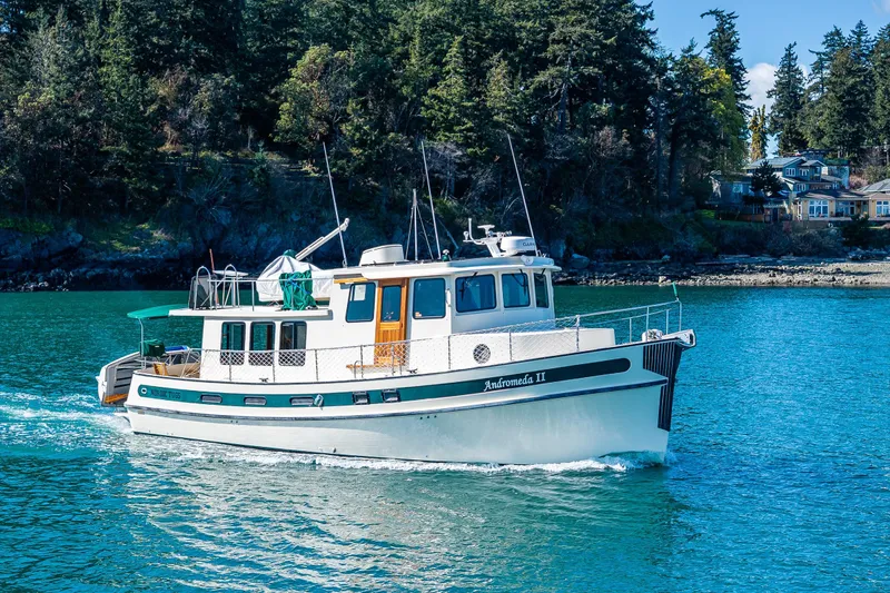 Slide: The Image of 1997 Nordic Tug 42 cruising on a scenic waterway with lush forested background. - 42