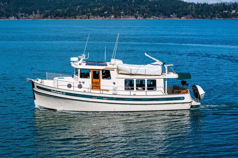 Slide: The Image of Nordic Tug 42, 1997 model, cruising on a serene blue lake with forested hills. - 47