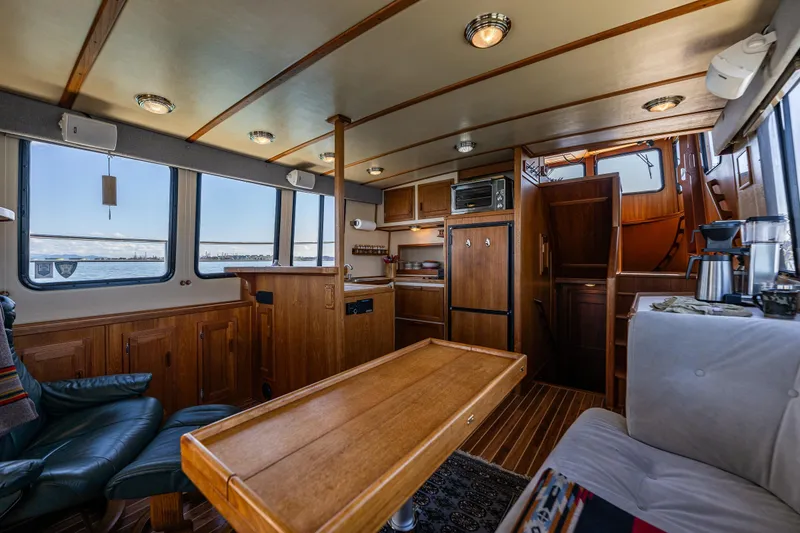 Slide: The Image of Interior of a 1997 Nordic Tug 42, featuring a cozy wooden cabin with seating and kitchen area. - 5