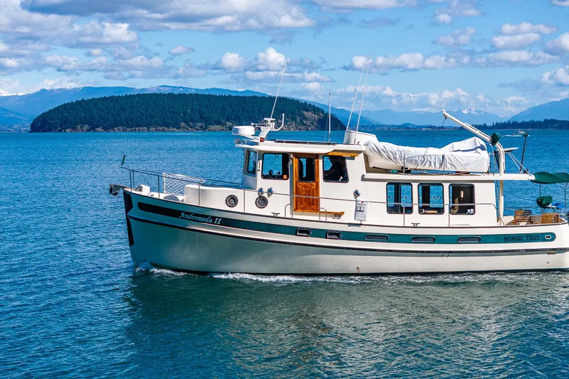 Slide: The Image of 1997 Nordic Tug 42 cruising on a scenic lake with mountainous backdrop. - 50