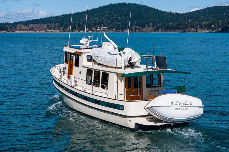 Slide: The Image of 1997 Nordic Tug 42 cruising on blue water with scenic forested background. - 51