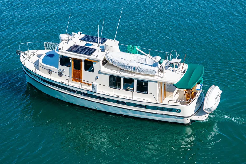 Slide: The Image of 1997 Nordic Tug 42 cruising on clear blue water, featuring solar panels and a covered deck. - 53