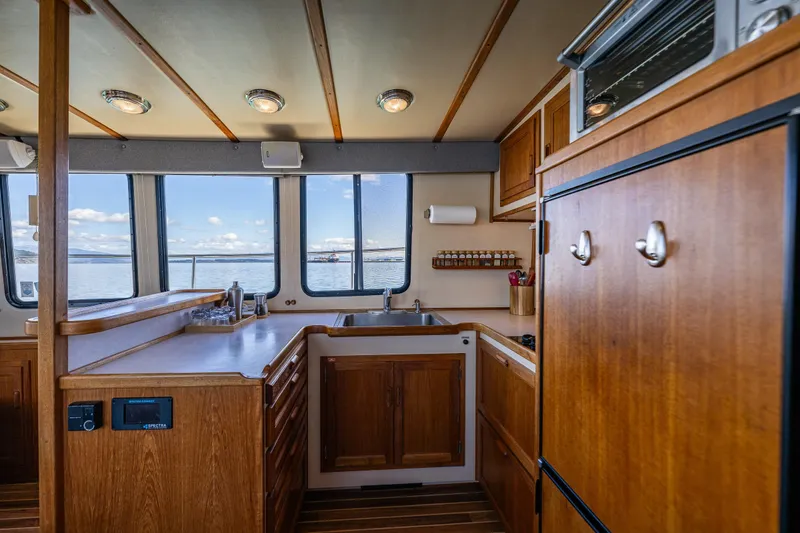 Slide: The Image of Cozy kitchen interior of a 1997 Nordic Tug 42 boat with wooden cabinetry and ocean view. - 7