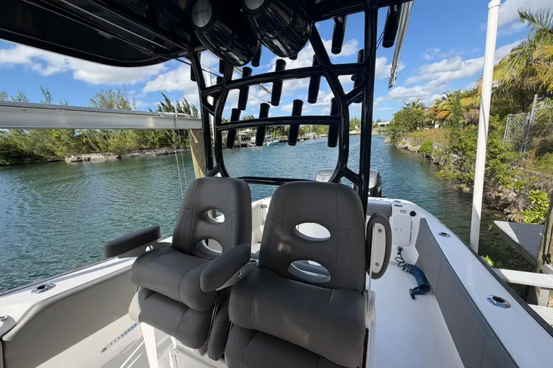 Slide: The Image of 2023 Cape Horn 32 XS boat interior with dual seats and rod holders on a sunny day. - 13