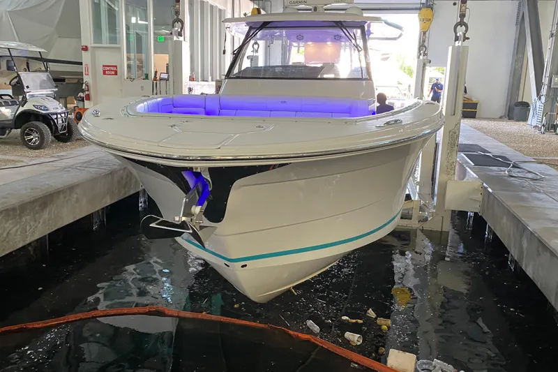 Slide: The Image of 2021 Regal 38 SAV boat in a marina, featuring sleek design and blue interior lighting. - 11