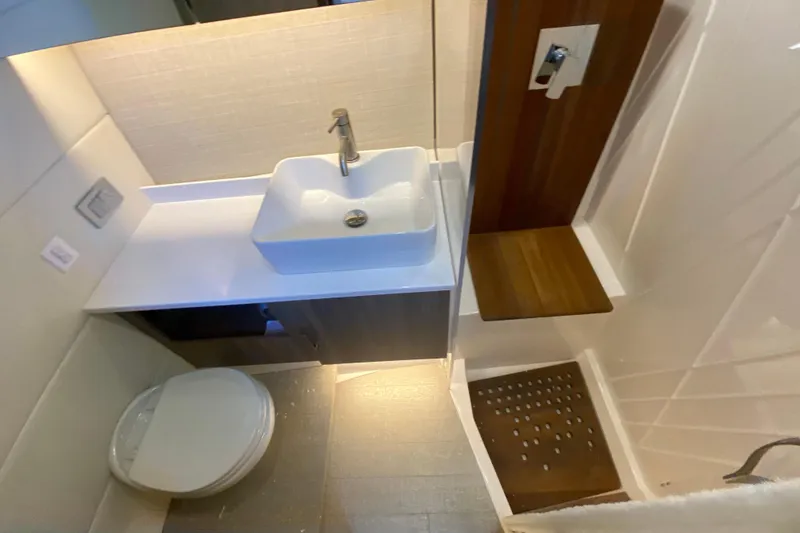 Slide: The Image of 2021 Regal 38 SAV bathroom with modern sink, toilet, and wooden shower seat. - 24