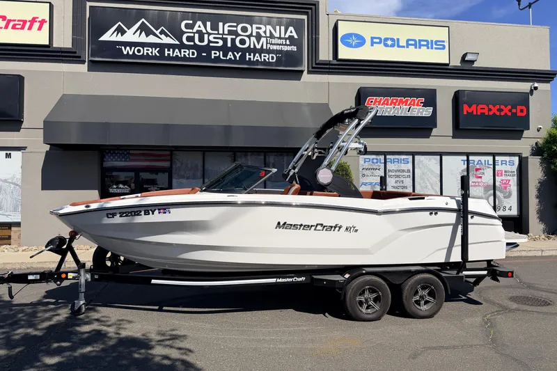 The Image of 2023 MasterCraft NXT23 boat on trailer outside California Custom dealership. - 0