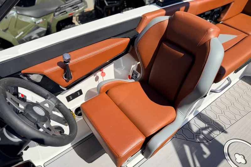 Slide: The Image of 2023 MasterCraft NXT23 boat interior with brown leather seating and steering wheel. - 10