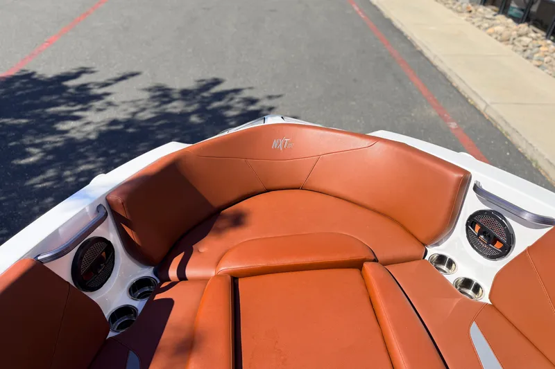 Slide: The Image of 2023 MasterCraft NXT23 boat interior with brown leather seating and cup holders. - 18