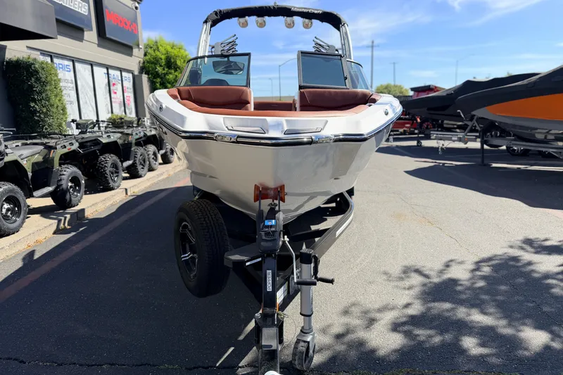 Slide: The Image of 2023 MasterCraft NXT23 boat on trailer, displayed outdoors at dealership. - 2