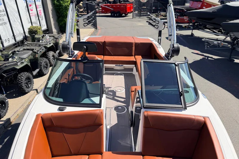 Slide: The Image of 2023 MasterCraft NXT23 boat with brown seating and sleek design in a showroom. - 21