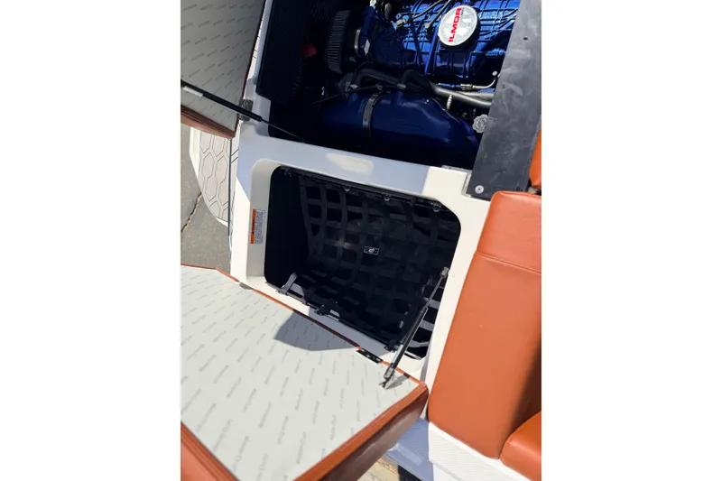 Slide: The Image of 2023 MasterCraft NXT23 boat engine compartment with storage area and brown seating. - 23