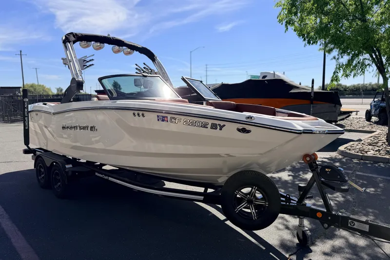 Slide: The Image of 2023 MasterCraft NXT23 boat on trailer, parked outdoors under clear sky. - 3