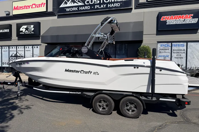 Slide: The Image of 2023 MasterCraft NXT23 boat on trailer outside dealership, showcasing sleek design and modern features. - 7