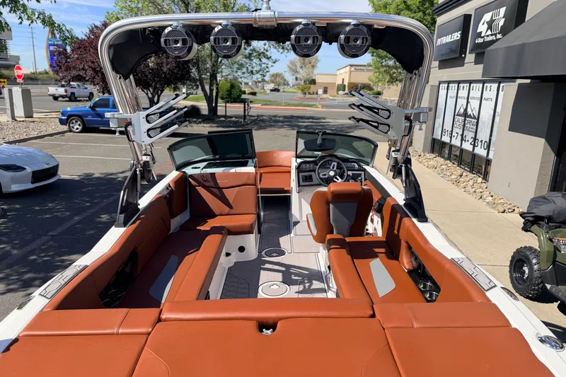 Slide: The Image of 2023 MasterCraft NXT23 boat with brown seating, sleek design, and modern dashboard in a parking lot. - 8