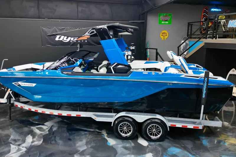 Slide: The Image of 2022 Nautique Super Air Nautique G25 Paragon boat in showroom, blue exterior. - 5