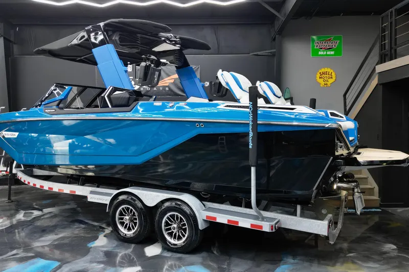 Slide: The Image of 2022 Nautique Super Air Nautique G25 Paragon boat in showroom, vibrant blue exterior. - 6