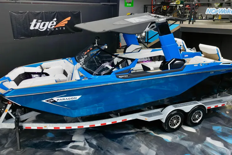 Slide: The Image of 2022 Nautique Super Air Nautique G25 Paragon boat in showroom, blue exterior, on trailer. - 9