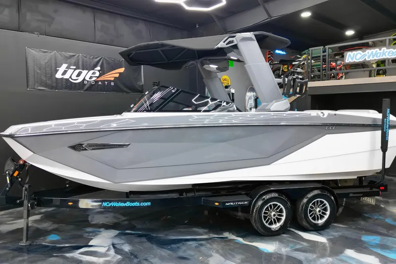 The Image of 2024 Nautique Super Air Nautique G23 boat displayed indoors on a trailer. - 1
