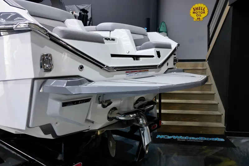 Slide: The Image of 2024 Nautique Super Air Nautique G23 boat rear view in showroom setting. - 17