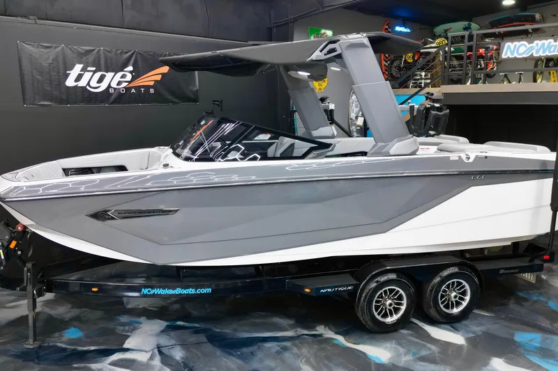 The Image of 2024 Nautique Super Air Nautique G23 boat displayed indoors on a trailer. - 2