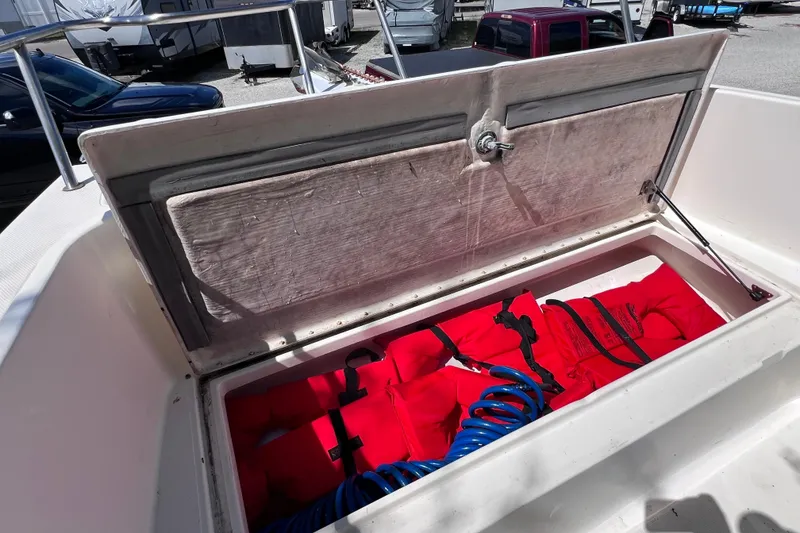 Slide: The Image of Open storage compartment on 1999 World Cat 246 SF boat with red life jackets and blue hose. - 14