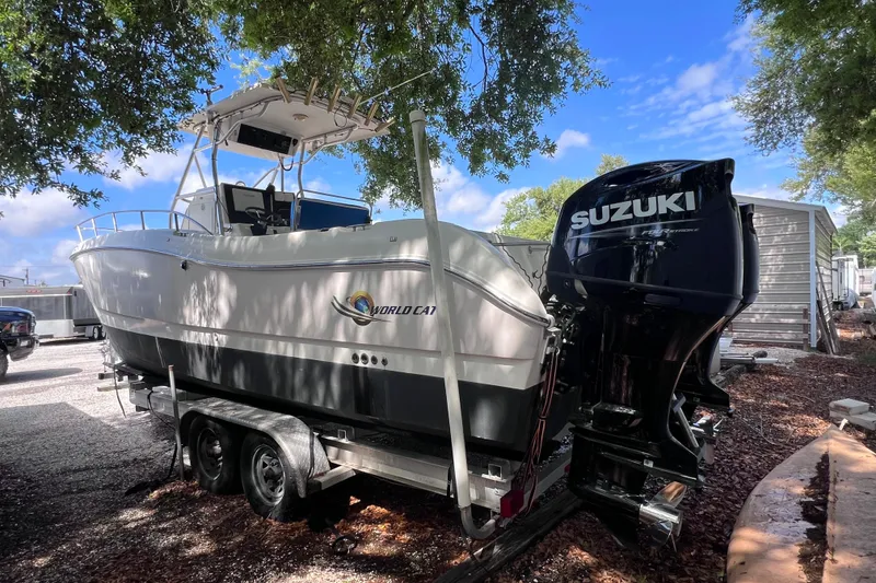 Slide: The Image of 1999 World Cat 246 SF boat on trailer with Suzuki outboard motor, parked outdoors. - 2